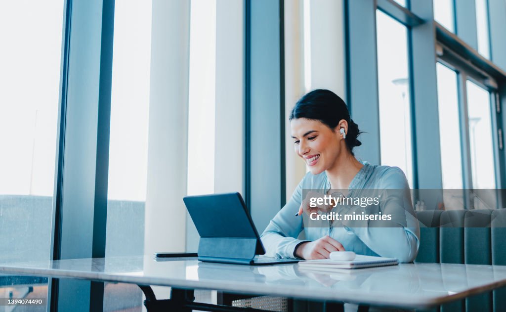 Beautiful Woman Wearing Earbuds And Watching Something Fun on Her Tablet