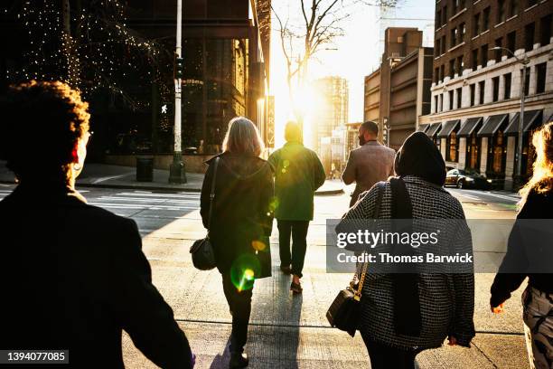 wide shot rear view of business people crossing downtown street - hijab woman from behind stock-fotos und bilder