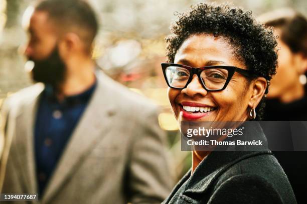 medium shot of smiling businesswoman on city street during commute - hoop earring stock pictures, royalty-free photos & images