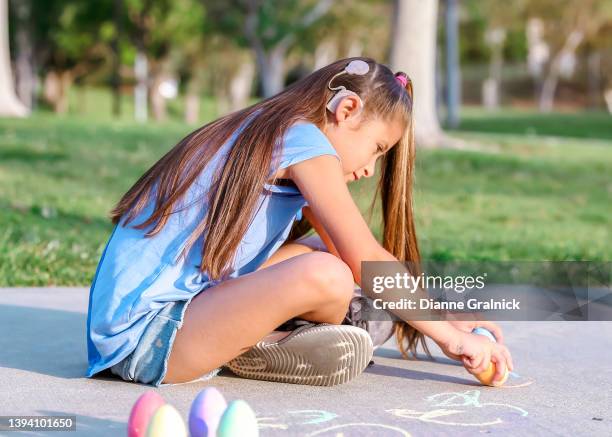 girl with cochlear implant playing with sidewalk chalk - cochlear implant stock pictures, royalty-free photos & images