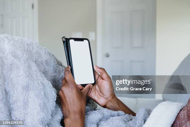 woman lounges in bed looking at smart phone with blank screen - mensch bett stock-fotos und bilder