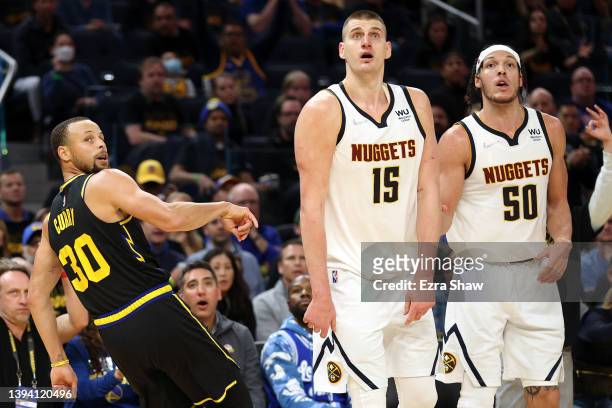 Nikola Jokic andf Aaron Gordon of the Denver Nuggets watch a three-point basket go in that was shot by Stephen Curry of the Golden State Warriors in...