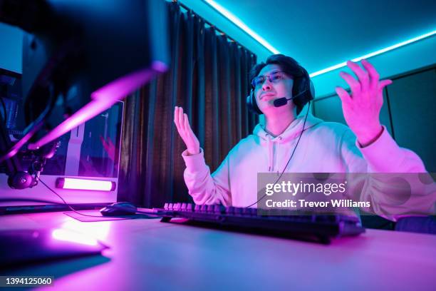 millennial-aged man looking frustrated while playing e-sports on his computer - subdue stockfoto's en -beelden