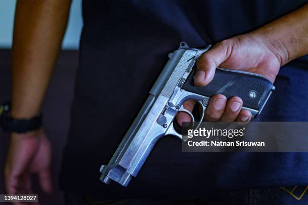 man holding hidden short gun in his hand. - shooting imagens e fotografias de stock