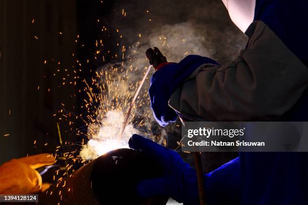 industrial welder with protective helmet in big hall welding metal profiles - industrial labourer stock pictures, royalty-free photos & images