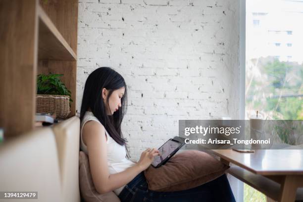 side view of a woman using an ipad - internet cafe stockfoto's en -beelden