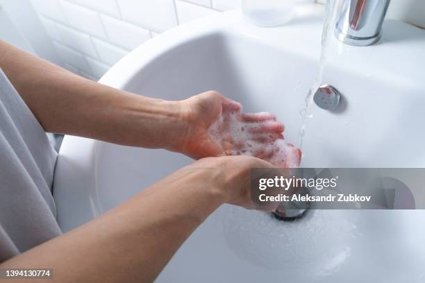 a woman washes and disinfects her hands with soap in the bathroom, at home or in a public place. disease prevention, sanitation. the concept of hygiene. dispenser with non-contact application of soap. compliance with pandemic and coronavirus measures. - ruhr stock-fotos und bilder