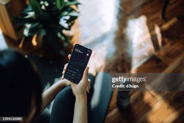 high angle view of young asian sports woman using nft investment wallet on smartphone, working with bitcoin technologies, investing or trading nft on cryptocurrency, digital asset, art work and digital ledger with mobile app after working out at home - sporthandel stock-fotos und bilder