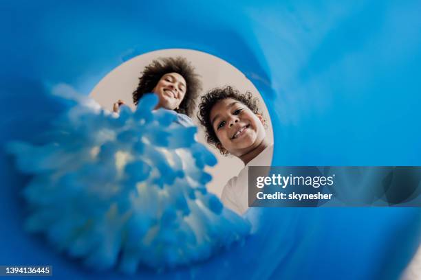 below view of single black mother and daughter dipping the mop into the bucket. - daily bucket stockfoto's en -beelden