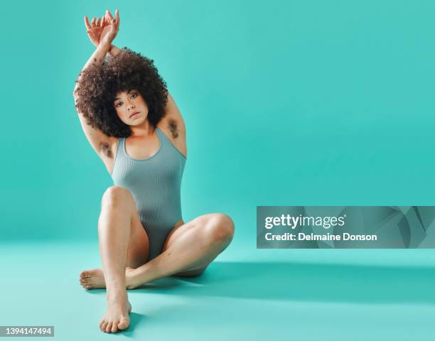 full body mixed race model sitting and showing armpit hair in studio - hairy woman stockfoto's en -beelden