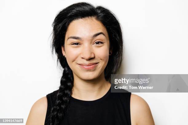 portrait of woman with long, black platted hair and raised eyebrow - sonrisa satisfecha fotografías e imágenes de stock