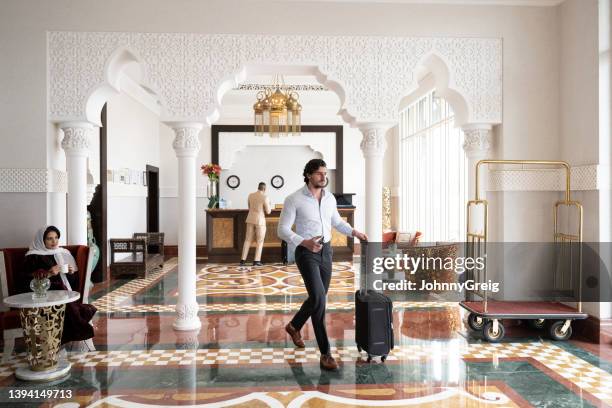 early 30s saudi businessman walking through hotel lobby - hotel de luxo imagens e fotografias de stock