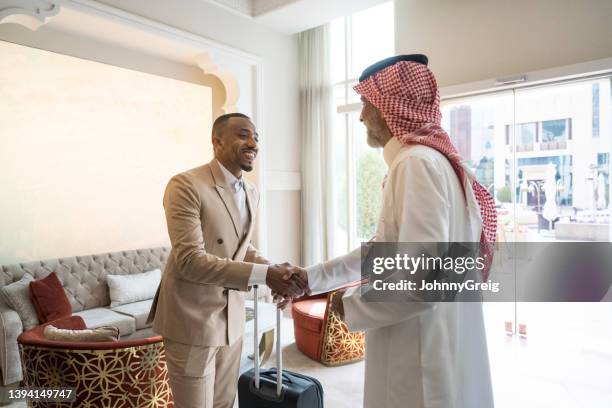 middle eastern and black businessmen shaking hands in hotel - riyadh culture stock pictures, royalty-free photos & images