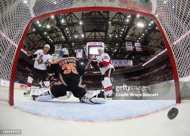 Nick Foligno and Chris Neil of the Ottawa Senators watch a shot by Chris Phillips enter the net in the second period against the New York Islanders...