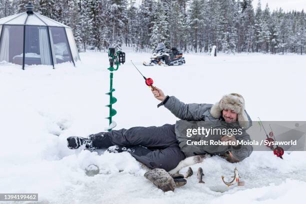 cheerful man catching a fish from ice hole, sweden - sverige vinter bildbanksfoton och bilder