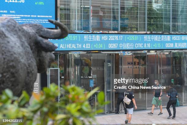Pedestrians walk by an electronic ticker displaying the numbers for the Hang Seng Index at the Exchange Square Complex, which houses the Hong Kong...