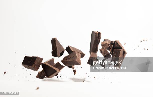 flying chocolate pieces, fresh dark brown chocolate fragments - chocolat stock-fotos und bilder