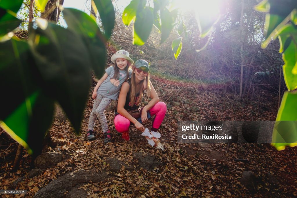 Mother and daughter in the forest looking at the camera with hats and casual clothes