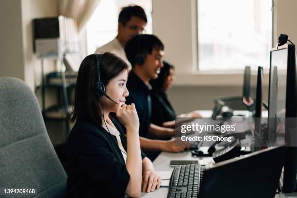 imprenditrice che indossa le cuffie durante l'utilizzo del computer - call centre asian foto e immagini stock