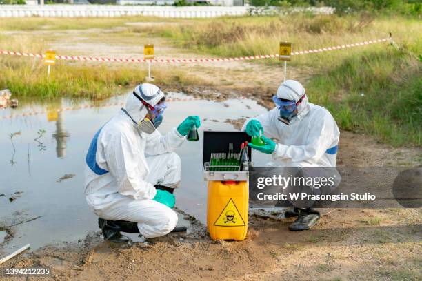 biologists take water from a chemically contaminated river, study its composition in a laboratory. - mono blanco traje protector fotografías e imágenes de stock