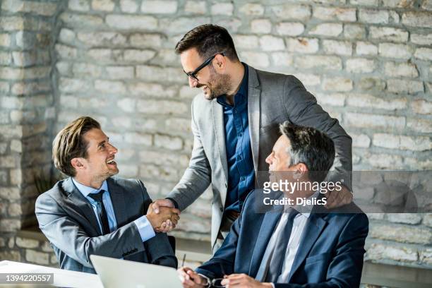 happy businessmen shaking hands in the office. - s ceo stock pictures, royalty-free photos & images