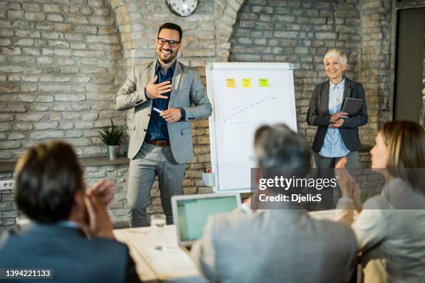 business people applauding to young businessman giving them a business presentation in the office. - sales pitch stock pictures, royalty-free photos & images
