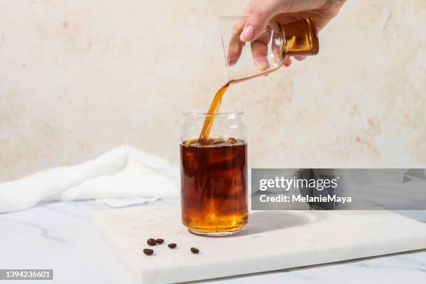 hand pouring coffee cold brew carajillo espresso ice coffee with ice cubes - ice coffee stock pictures, royalty-free photos & images