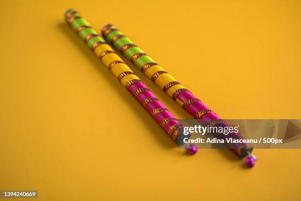 dandiya sticks on a yellow background - dandiya stock pictures, royalty-free photos & images