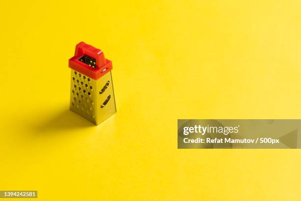 metal grater with a red handle on a bright yellow background - metal grate fotografías e imágenes de stock