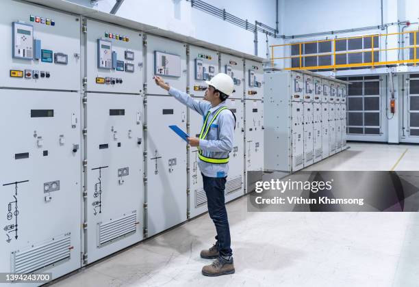 engineer working at switch panel of switchgear room, young electrician working at electrical room with tablet, industrial service engineer checking conducts of control panel at power plant, energy - schaltschrank stock-fotos und bilder