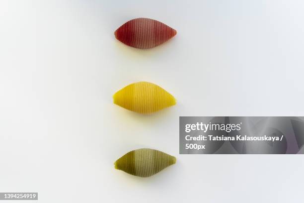 red,yellow and green conchiglioni on a white background - conchiglie stockfoto's en -beelden