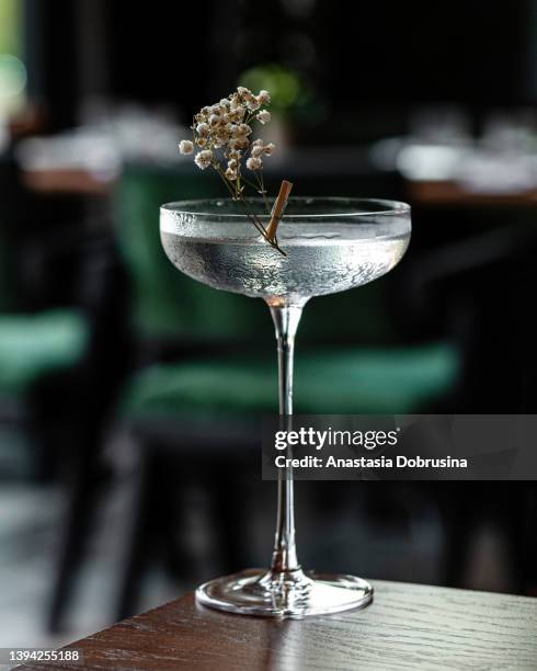 glass goblet of transparent cocktail garnished with flowers - aperitif stockfoto's en -beelden