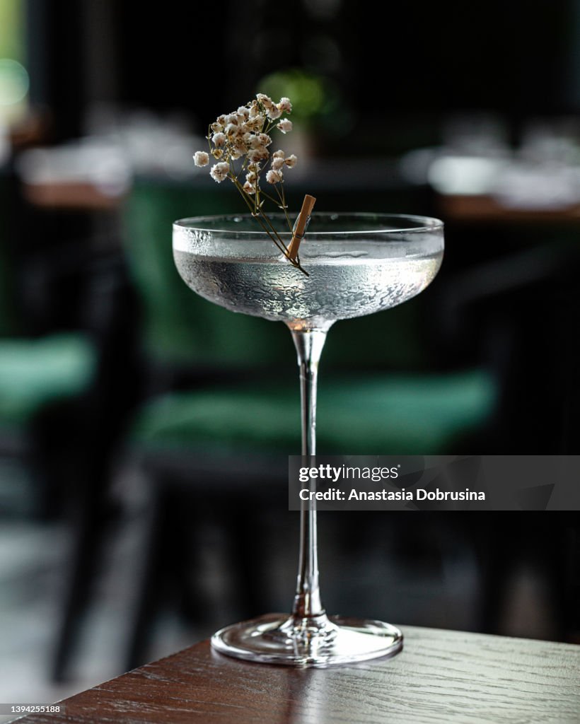 Glass goblet of transparent cocktail garnished with flowers