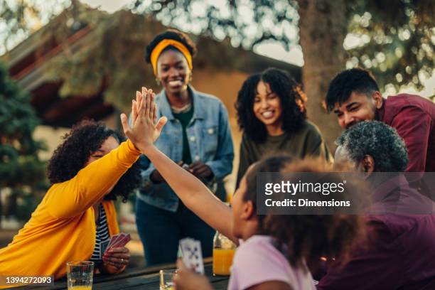 girl and grandmother high five during playing cards with family members - rivalry stock pictures, royalty-free photos & images
