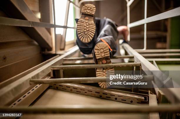 niedriger winkel eines arbeiters, der eine leiter in einer erzverarbeitungsfabrik erklimmt - schuhsohle stock-fotos und bilder