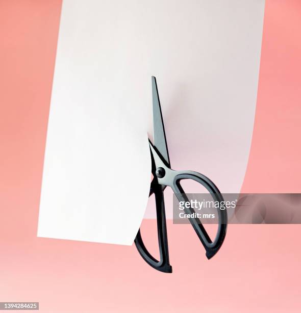 scissors cutting paper - cortar fotografías e imágenes de stock