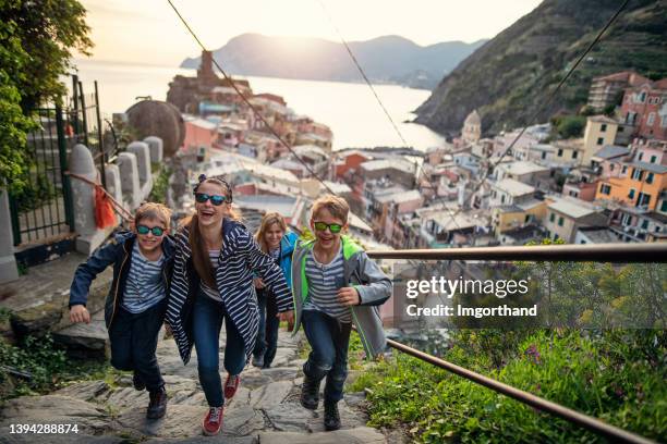 famiglia turistica che corre al punto panoramico di vernazza, cinque terre, italia - four people smiling foto e immagini stock