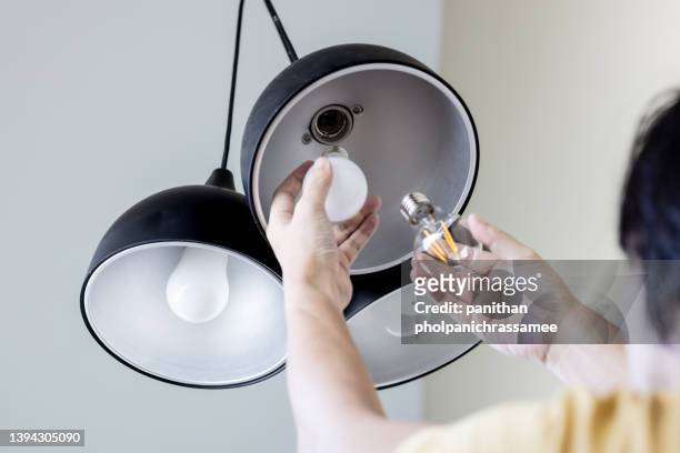 close up hand change to led bulb in home. concept for home improvement and green house. - bulb stock pictures, royalty-free photos & images