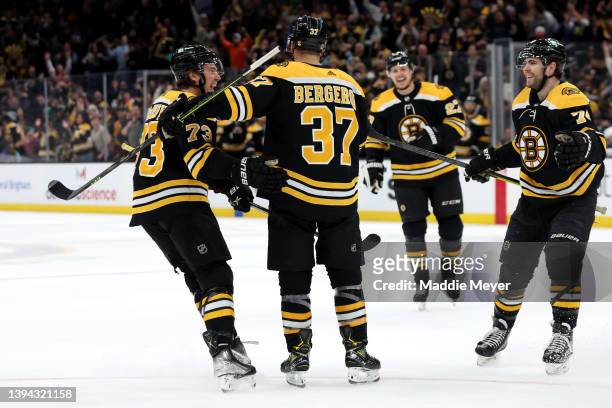 Patrice Bergeron of the Boston Bruins celebrates with Charlie McAvoy and Jake DeBrusk after scoring his third goal for a hat trick during the third...