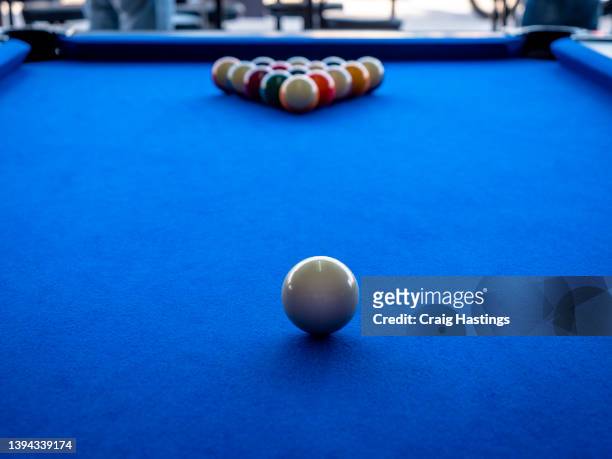 macro shot of american style blue cloth covered billiards pool table. no people in bar playing pool starting the game by breaking the full rack of balls. concept piece for sport, winning, success and competition. beating ones opponent. - billiard ball game stockfoto's en -beelden
