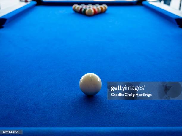 macro shot of american style blue cloth covered billiards pool table. no people in bar playing pool starting the game by breaking the full rack of balls. concept piece for sport, winning, success and competition. beating ones opponent. - billiard ball game stockfoto's en -beelden