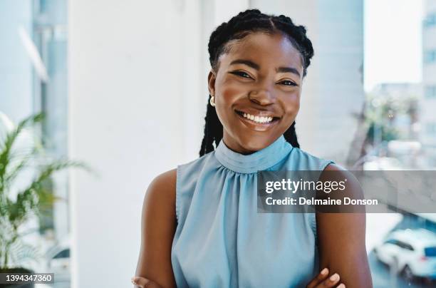 confident young black businesswoman standing at a window in an office alone - huvudbild bildbanksfoton och bilder