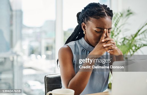 Stressed black businesswoman working on a laptop in an office alone Stressed black businesswoman working on a laptop in an office alone