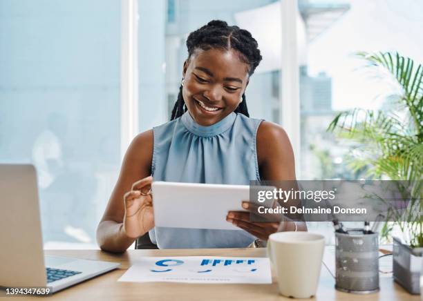 selbstbewusste junge afrikanische geschäftsfrau, die ein digitales tablet benutzt, während sie grafiken und daten allein in einem büro überprüft - african american woman with tablet stock-fotos und bilder