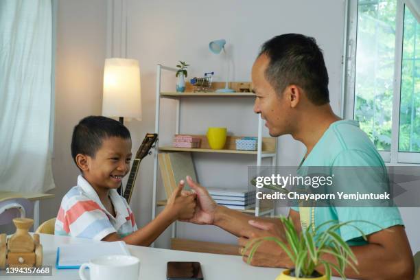 asian father and son playing a thumb wars. - thumb war stock pictures, royalty-free photos & images