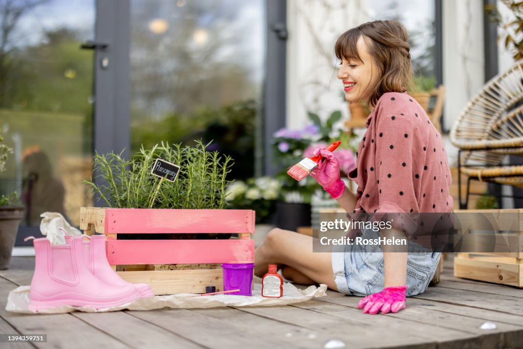 Woman painting wooden box, doing some renovating housework outdoors
