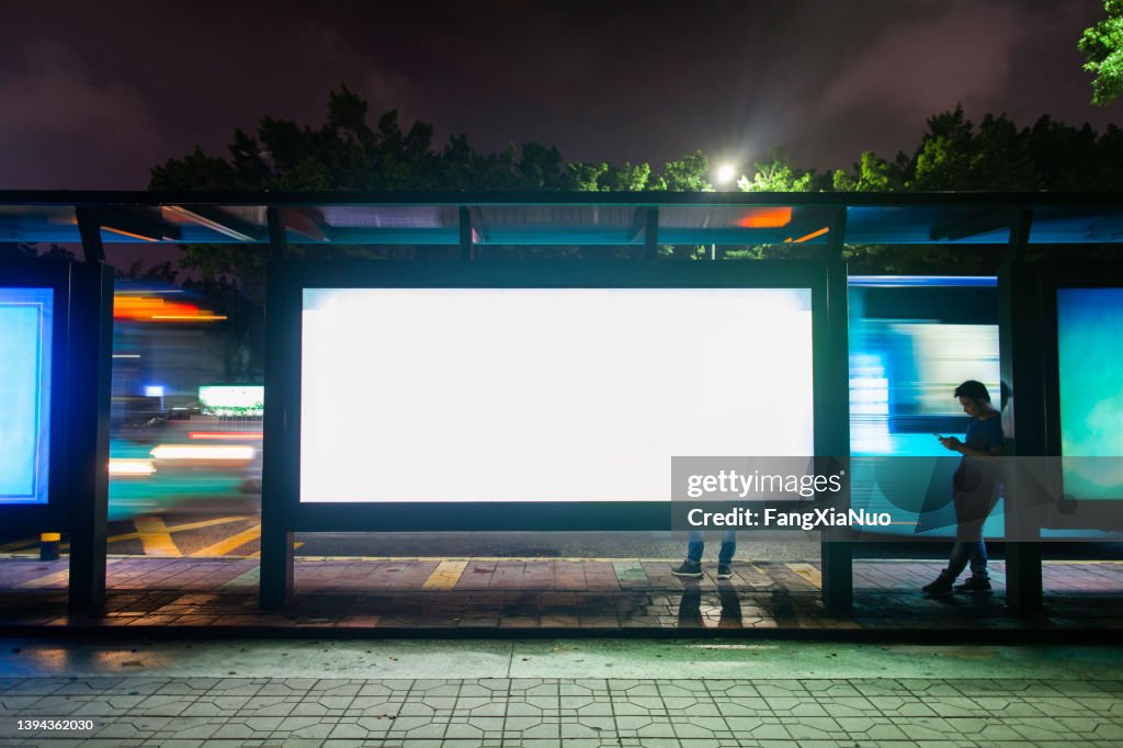 Junger Mann, der an der Bushaltestelle zur Hauptverkehrszeit in Shenzhen, China, auf öffentliche Verkehrsmittel wartet