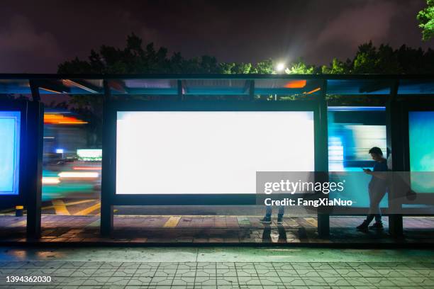 young man waiting for public transportation at rush hour bus stop in shenzhen, china - advertisement stockfoto's en -beelden