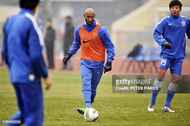 French striker Nicolas Anelka warms up with teammates before his team Shanghai Shenhua plays in a friendly match against Hunan Xiangtao at their...