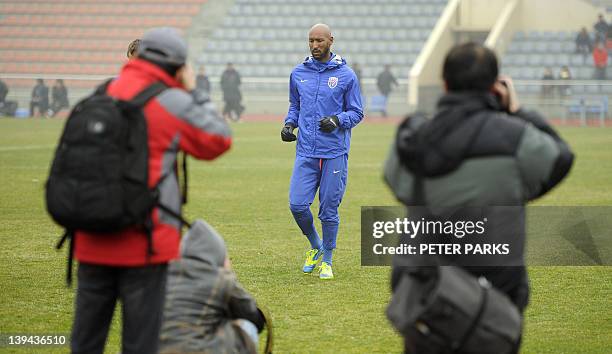 Photographers shoot French striker Nicolas Anelka as he warms up before his team Shanghai Shenhua plays in a friendly match against Hunan Xiangtao at...